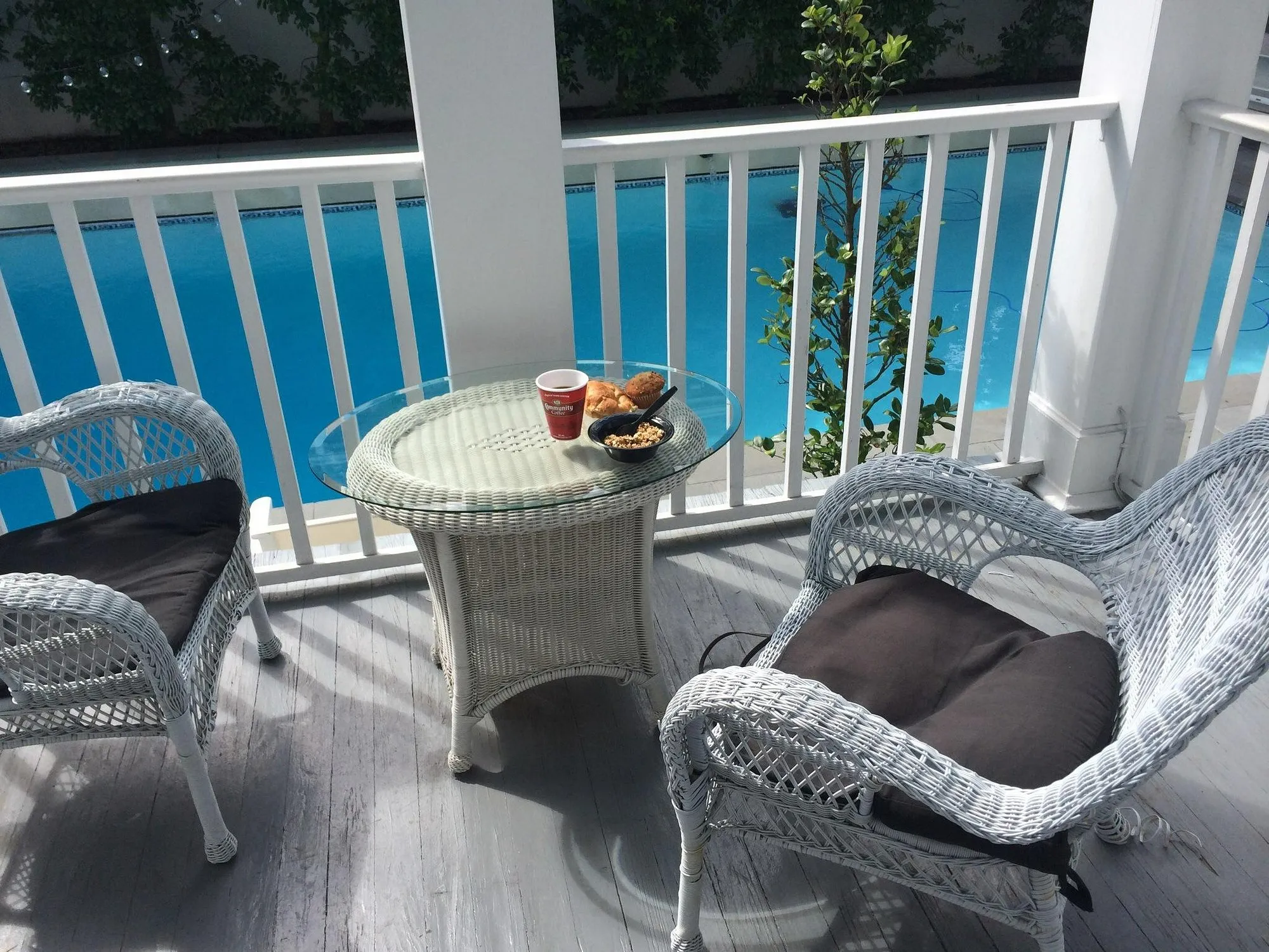 Private balcony at Melrose Mansion with white wicker furniture overlooking the pool on Esplanade Avenue